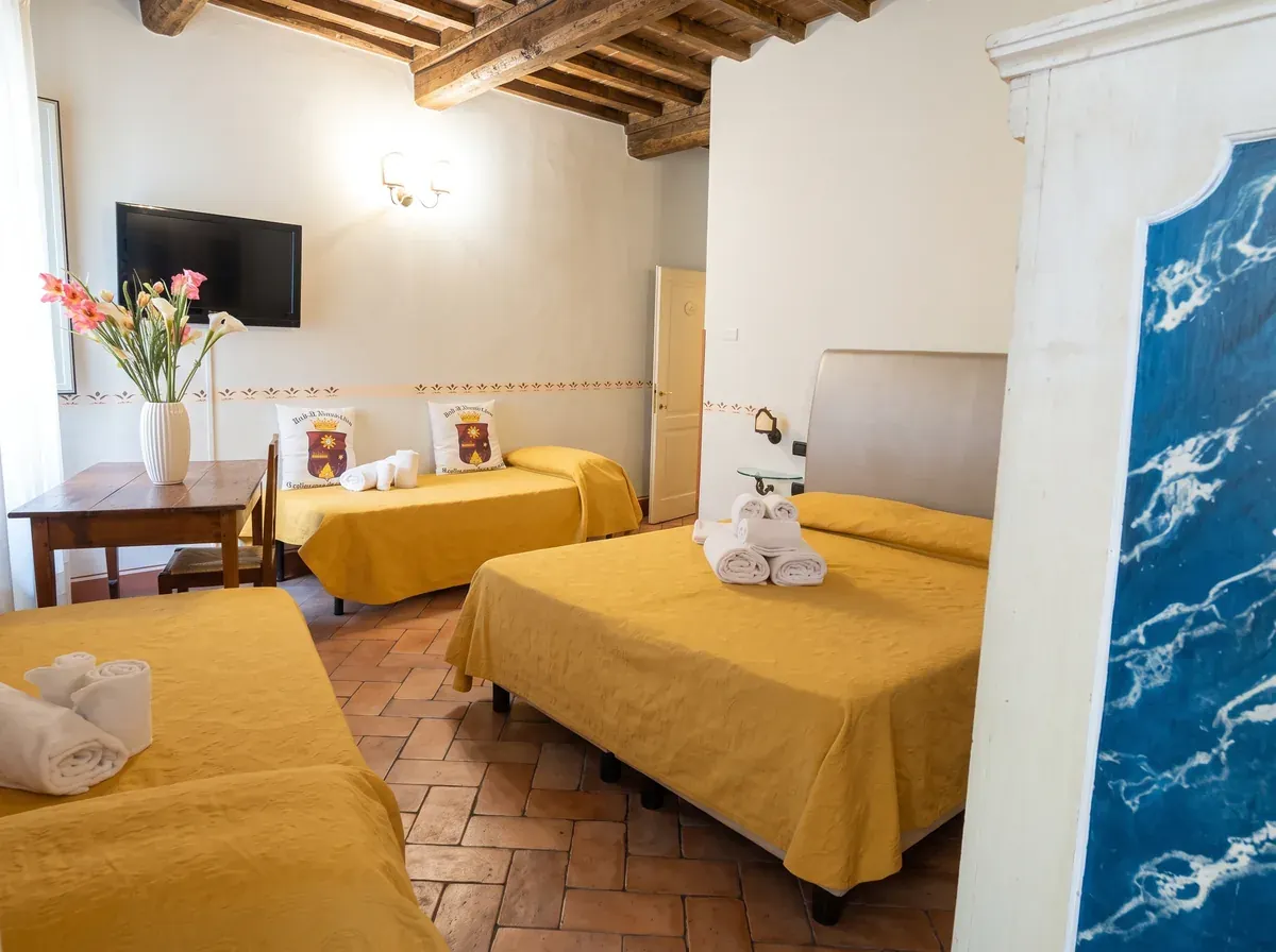 Camera quadrupla: letto matrimoniale e due letti singoli con copriletti ocra