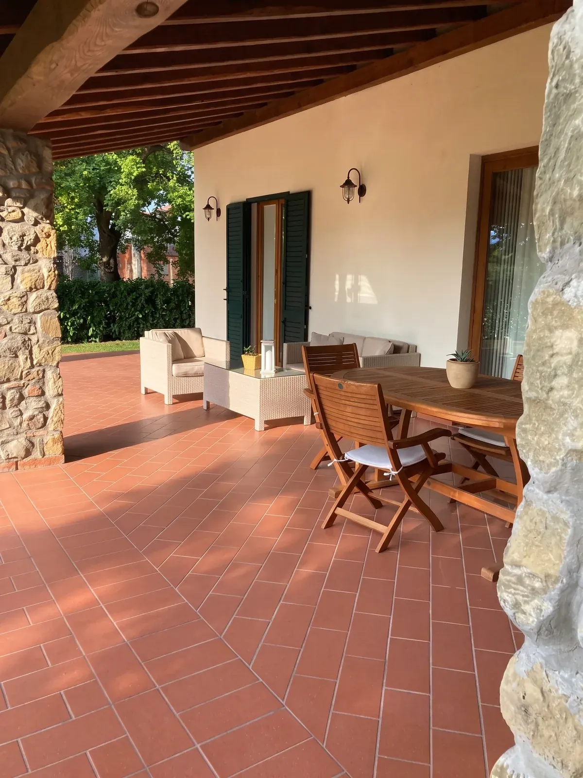 La terrazza coperta con il tavolo di legno e le poltroncine